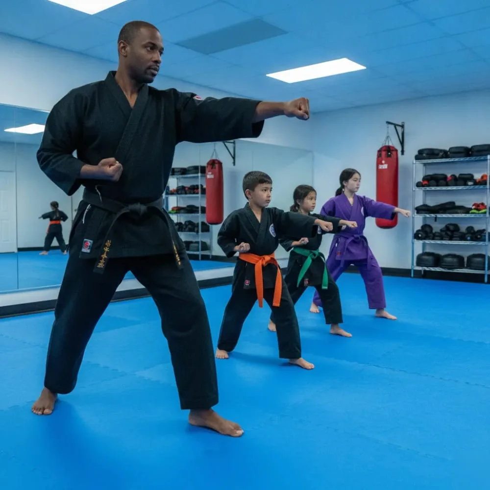 Karate school instructor training diverse students in group class at El Cajon dojo